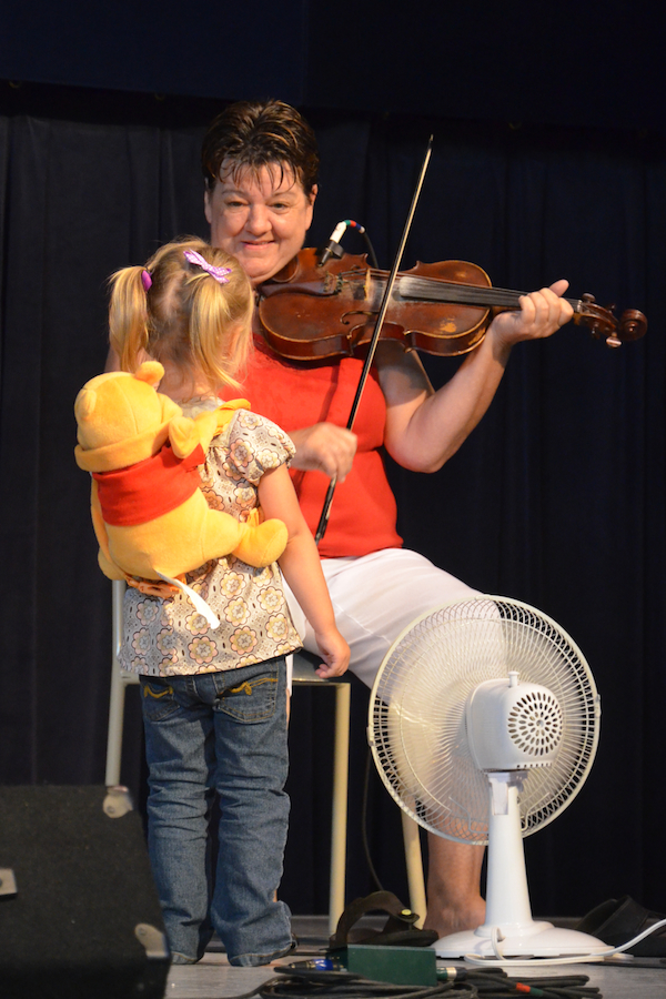 Brenda Stubbert on fiddle smiling at her granddaughter