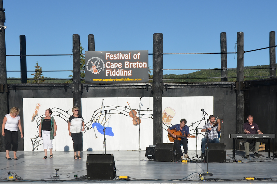 Leanne Aucoin, Kay Hanrahan, and Betty Matheson step-dancing to the music of Brent Aucoin on fiddle, accompanied by Mike Hall on keyboard, and Paul MacDonald on guitar
