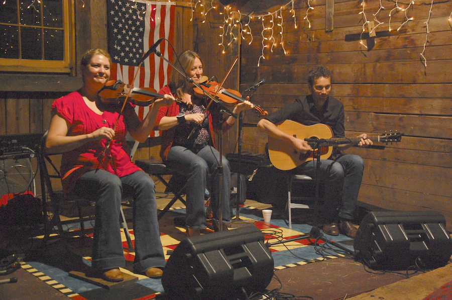 Photo of Andrea Beaton and Wendy MacIsaac on fiddles accompanied by Seph Peters on guitar